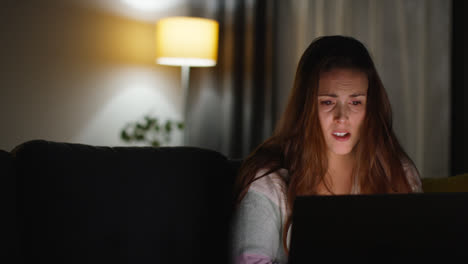 Anxious-Woman-Sitting-On-Sofa-At-Home-At-Night-Looking-At-Laptop-Concerned-About-Social-Media-Or-Bad-News-10